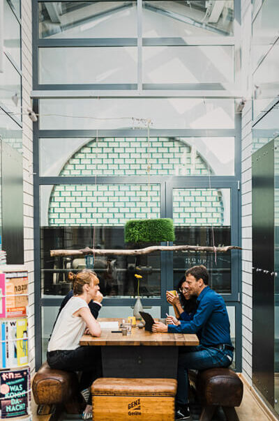 Drei Personen sitzen an einem Tisch in einem modernen Bürogebäude.